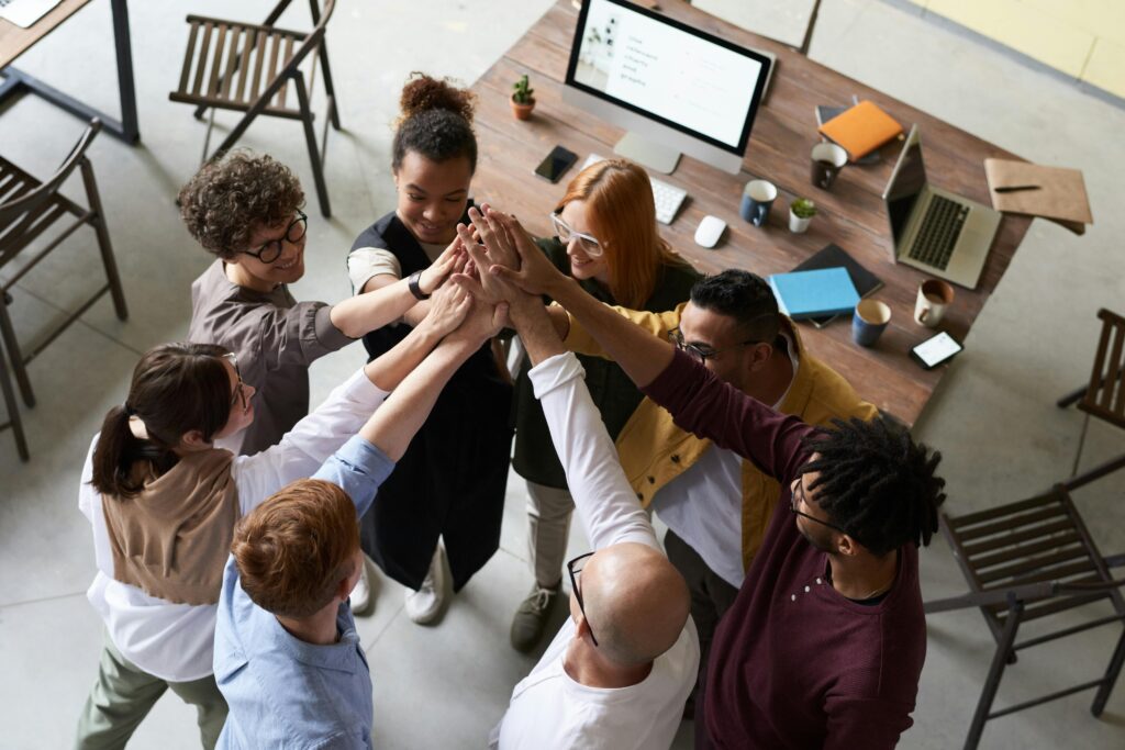 pexels photo 3184434 3184434 A diverse group of colleagues giving a high five during a corporate meeting indoors.